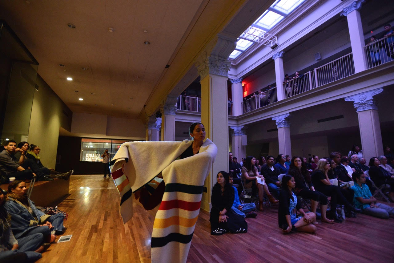 One dancer in a hand woven blanket among an audience