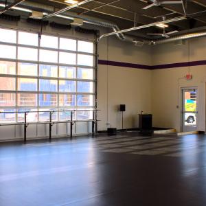 An image of the Nexus dance studio, with a wall of windows and black Marley floor