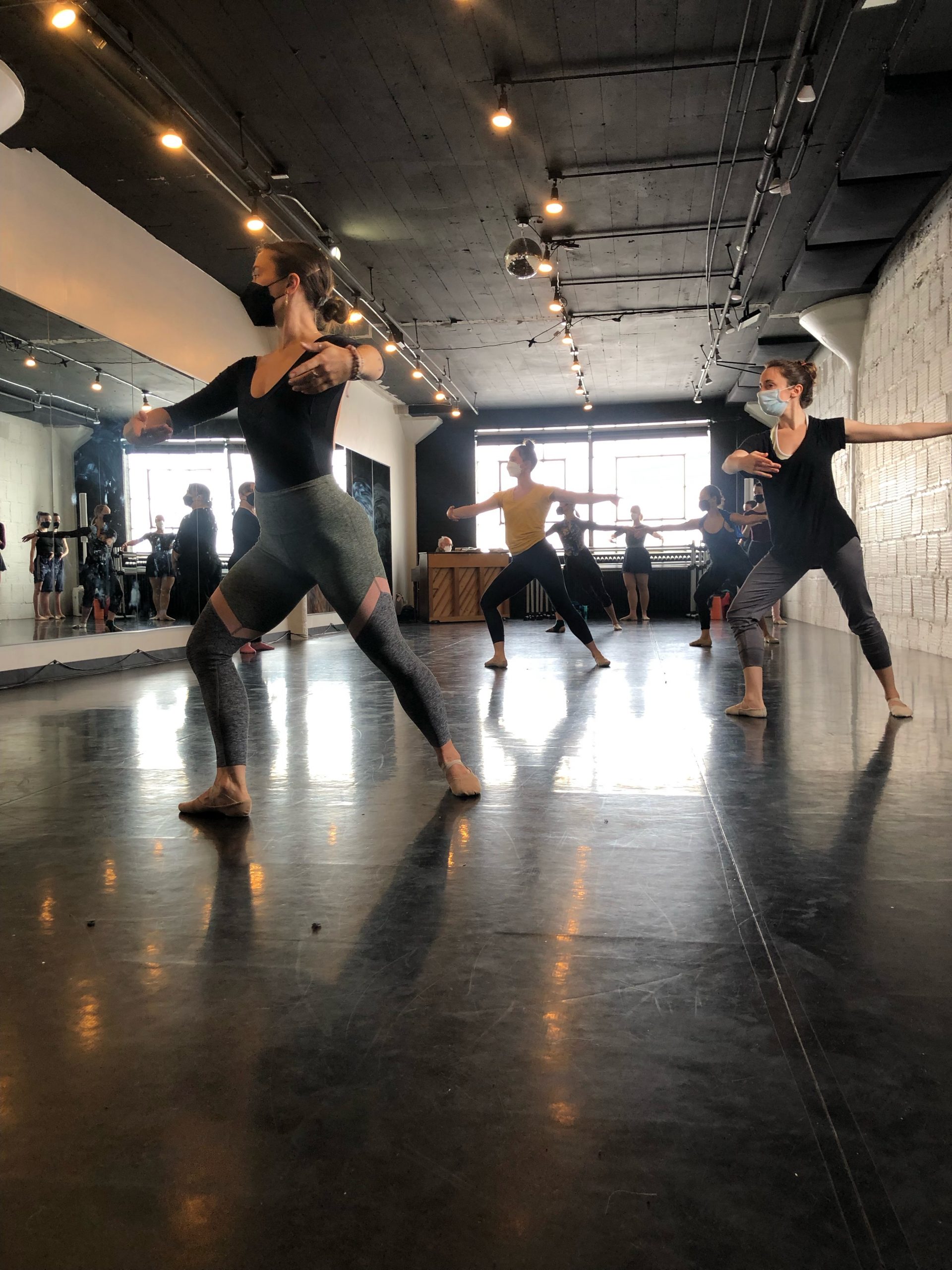 A photo of dancers in fourth position practicing a ballet combination