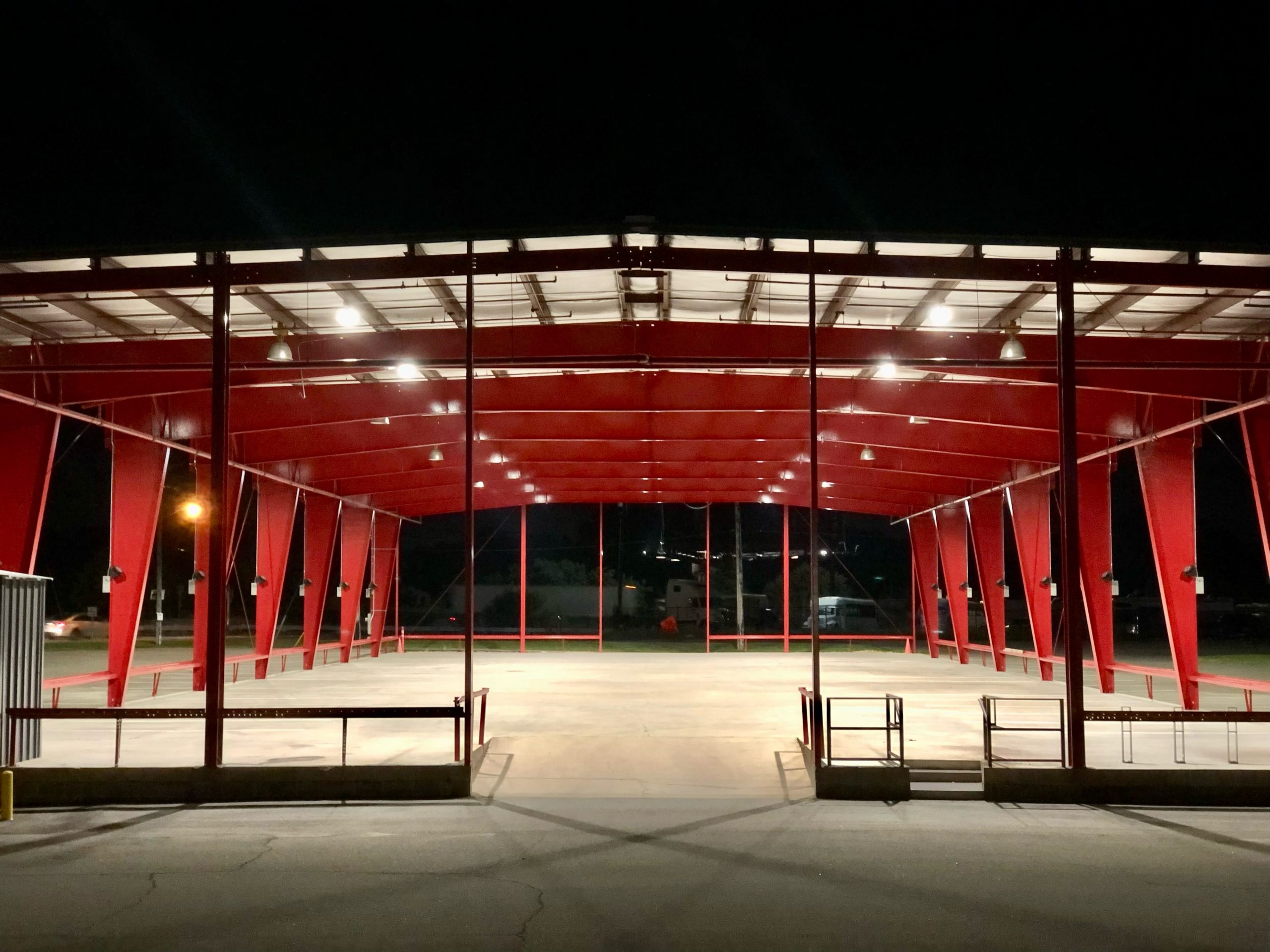 Image of the performance location: a large red metalic structure with an open concrete base