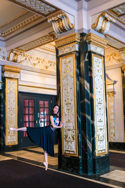 Yuki Tokuda, a Japanese woman, stands en pointe in an ornate foyer