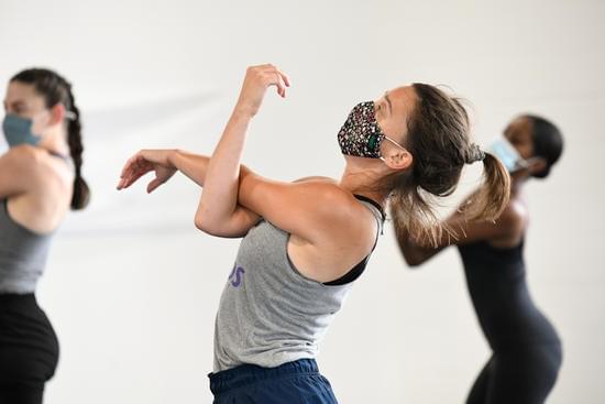 two light-skinned and one dark-skinned dancer capture their left arms in the crook of their right arms