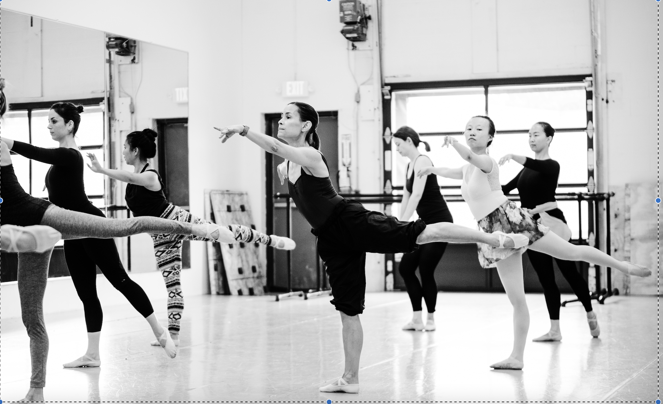 Several dancers in a studio practice their second arabesque