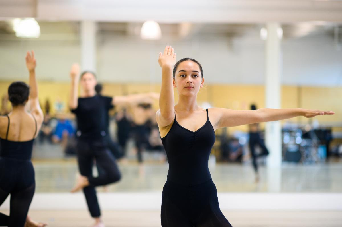 Several dancers dressed in black take the figure-4 pose in the Horton Technique